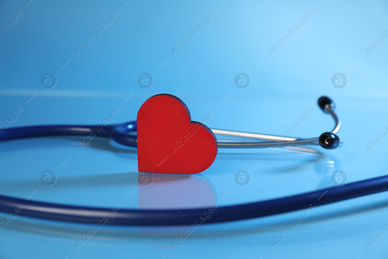 Stethoscope and red decorative heart on light blue background, closeup Photo of Stethoscope and red decorative heart on light blue background, closeup