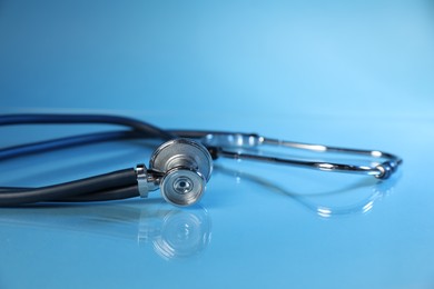 Photo of Stethoscope on light blue background, closeup. Medical tool