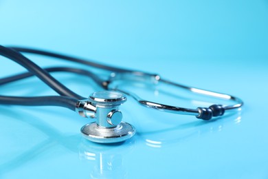 Photo of Stethoscope on light blue background, closeup. Medical tool