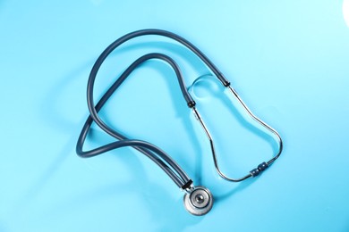 Photo of Stethoscope on light blue background, top view