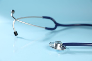 Photo of Stethoscope on light blue background, closeup. Medical tool