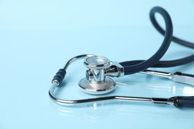 Photo of Stethoscope on light blue background, closeup. Medical tool
