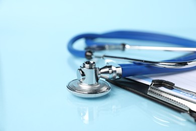 Photo of Stethoscope on light blue background, closeup. Space for text