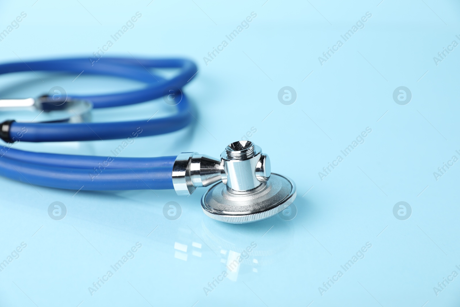 Photo of Stethoscope on light blue background, closeup. Space for text