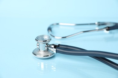 Photo of Stethoscope on light blue background, closeup. Space for text