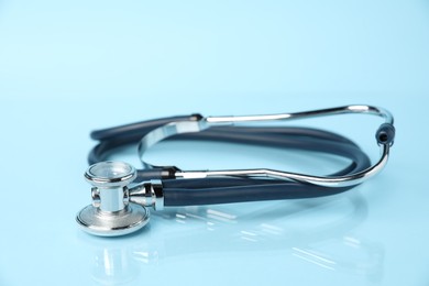 Photo of Stethoscope on light blue background, closeup. Medical tool