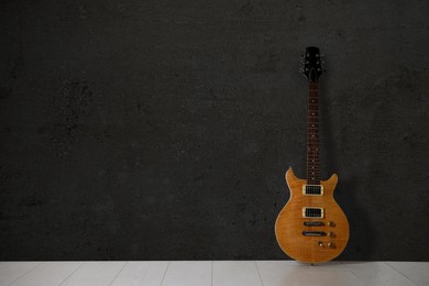 Image of Modern electric guitar on floor near black grunge wall. Space for text