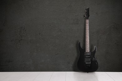 Image of Modern electric guitar on floor near dark grey grunge wall. Space for text