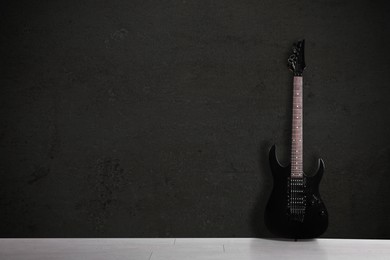 Image of Modern electric guitar on floor near black grunge wall. Space for text