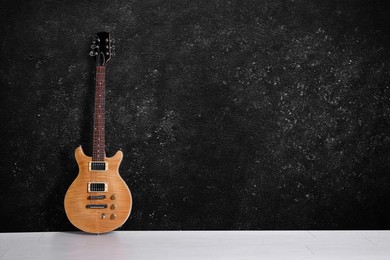 Image of Modern electric guitar on floor near black grunge wall. Space for text