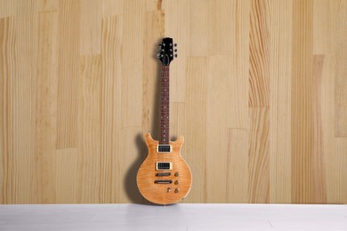 Image of Modern electric guitar on floor near wooden wall