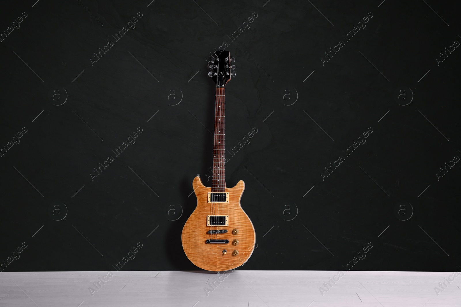 Image of Modern electric guitar on floor near black grunge wall