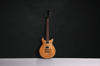 Image of Modern electric guitar on floor near black grunge wall