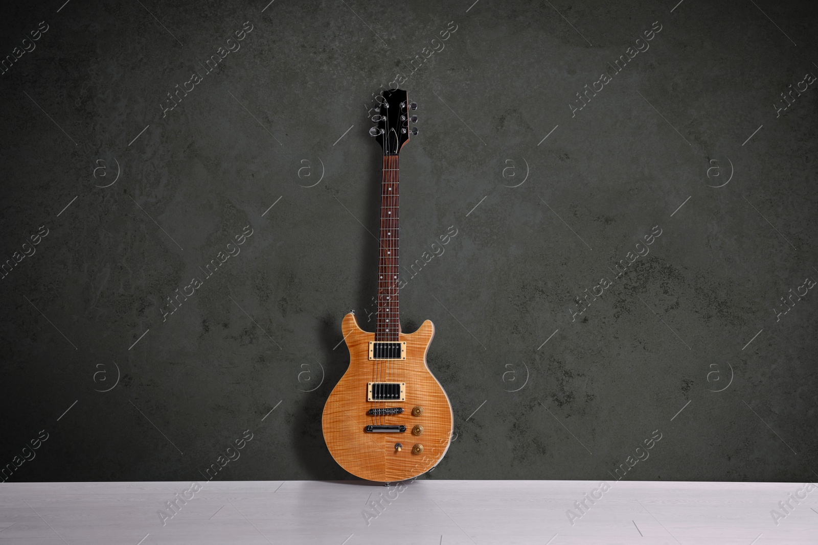 Image of Modern electric guitar on floor near dark grey grunge wall