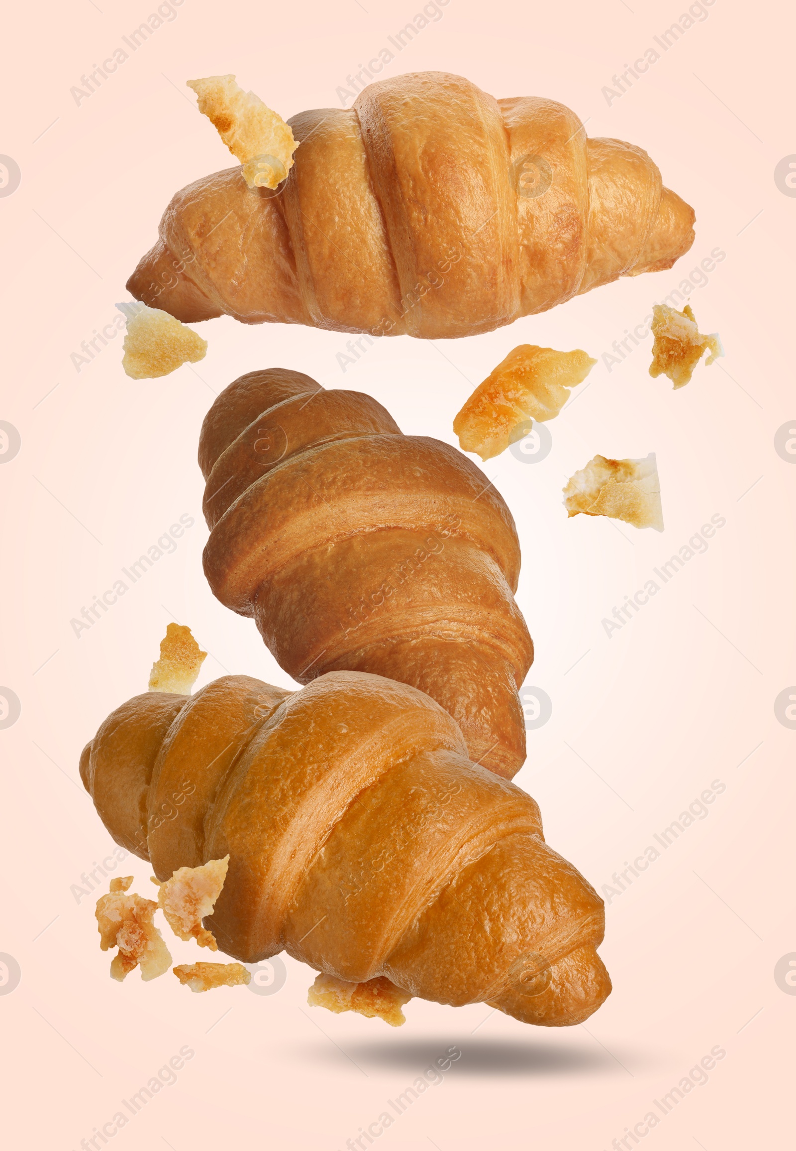 Image of Delicious croissants and crumbs falling on pink beige background. Puff pastry