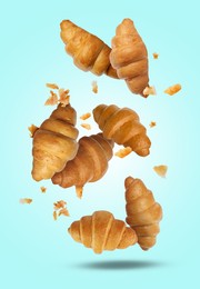 Image of Delicious croissants and crumbs falling on light blue background. Puff pastry