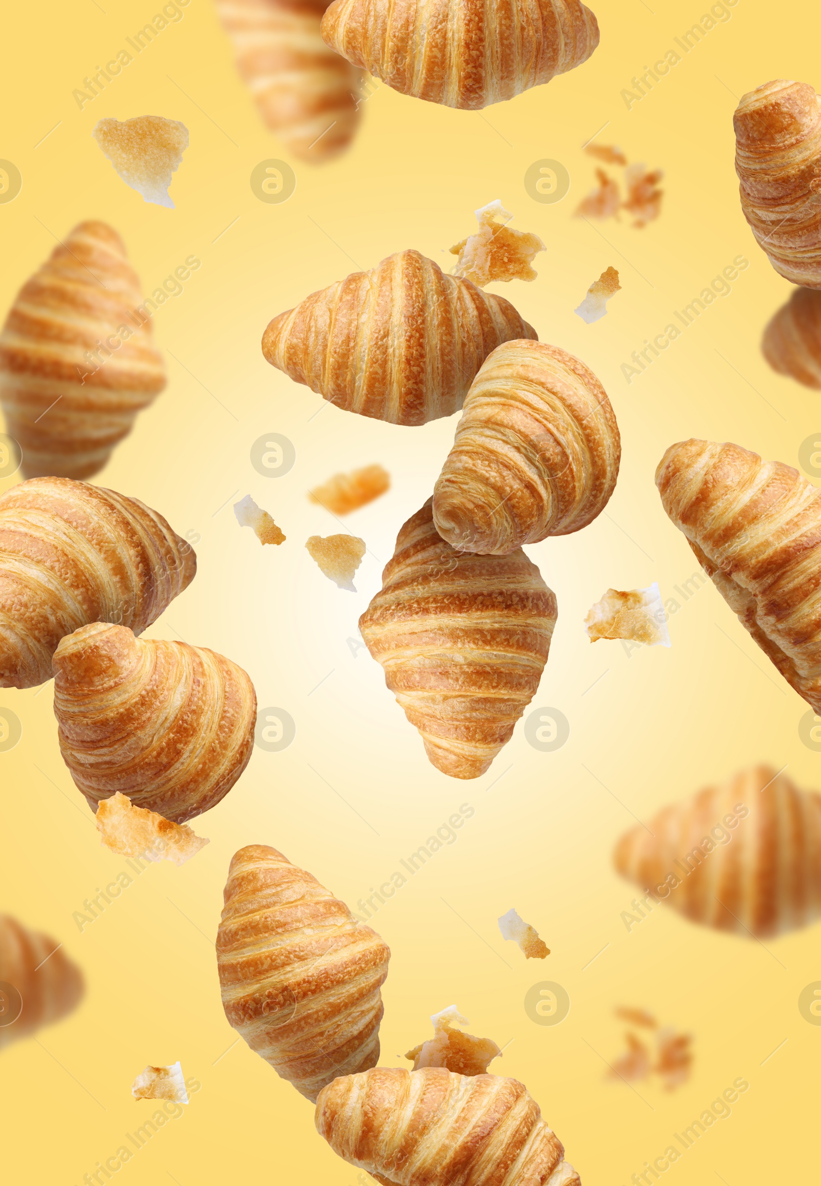 Image of Delicious croissants and crumbs in air on golden background. Puff pastry