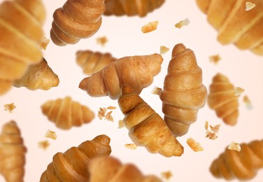 Image of Delicious croissants and crumbs in air on white background. Puff pastry