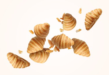 Image of Delicious croissants and crumbs in air on white background. Puff pastry