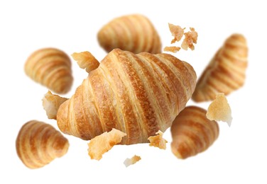 Image of Delicious croissants and crumbs in air on white background. Puff pastry