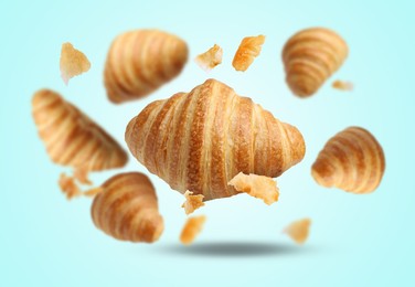 Image of Delicious croissants and crumbs falling on light blue background. Puff pastry