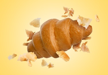 Image of Delicious croissant and crumbs in air on golden background. Puff pastry