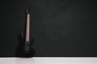 Image of Modern electric guitar on floor near black grunge wall. Space for text