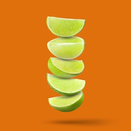 Image of Fresh lime slices falling on dark orange background