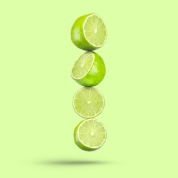 Image of Fresh lime slices falling on light green background