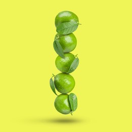 Image of Fresh whole lime falling on yellow background