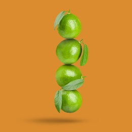 Image of Fresh whole lime falling on dark orange background