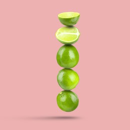 Image of Fresh juicy limes falling on pink background