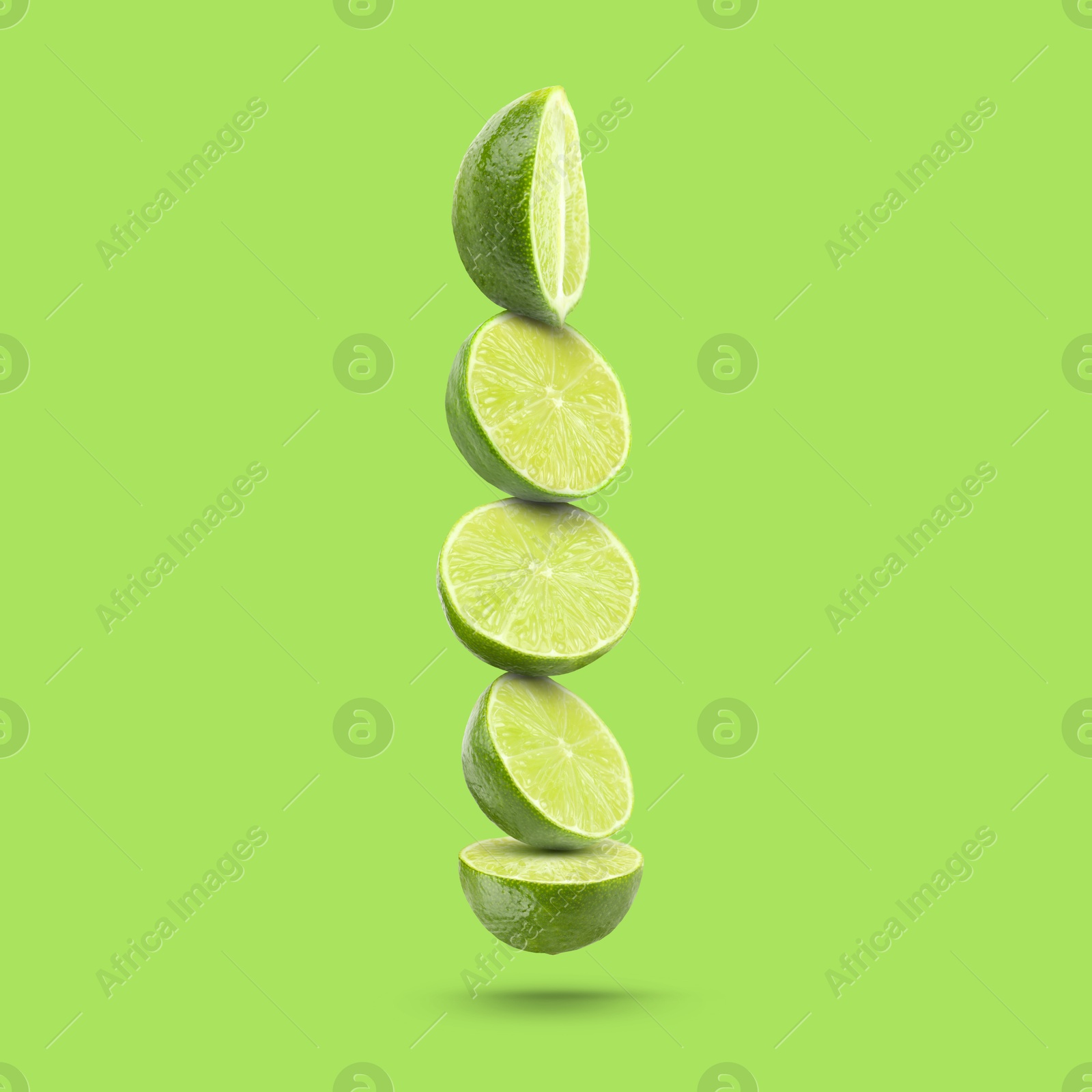 Image of Fresh lime slices falling on light green background