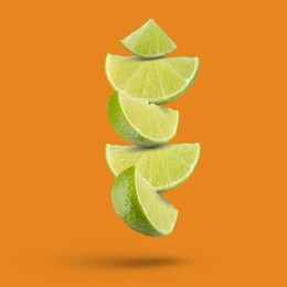 Image of Fresh lime slices falling on dark orange background