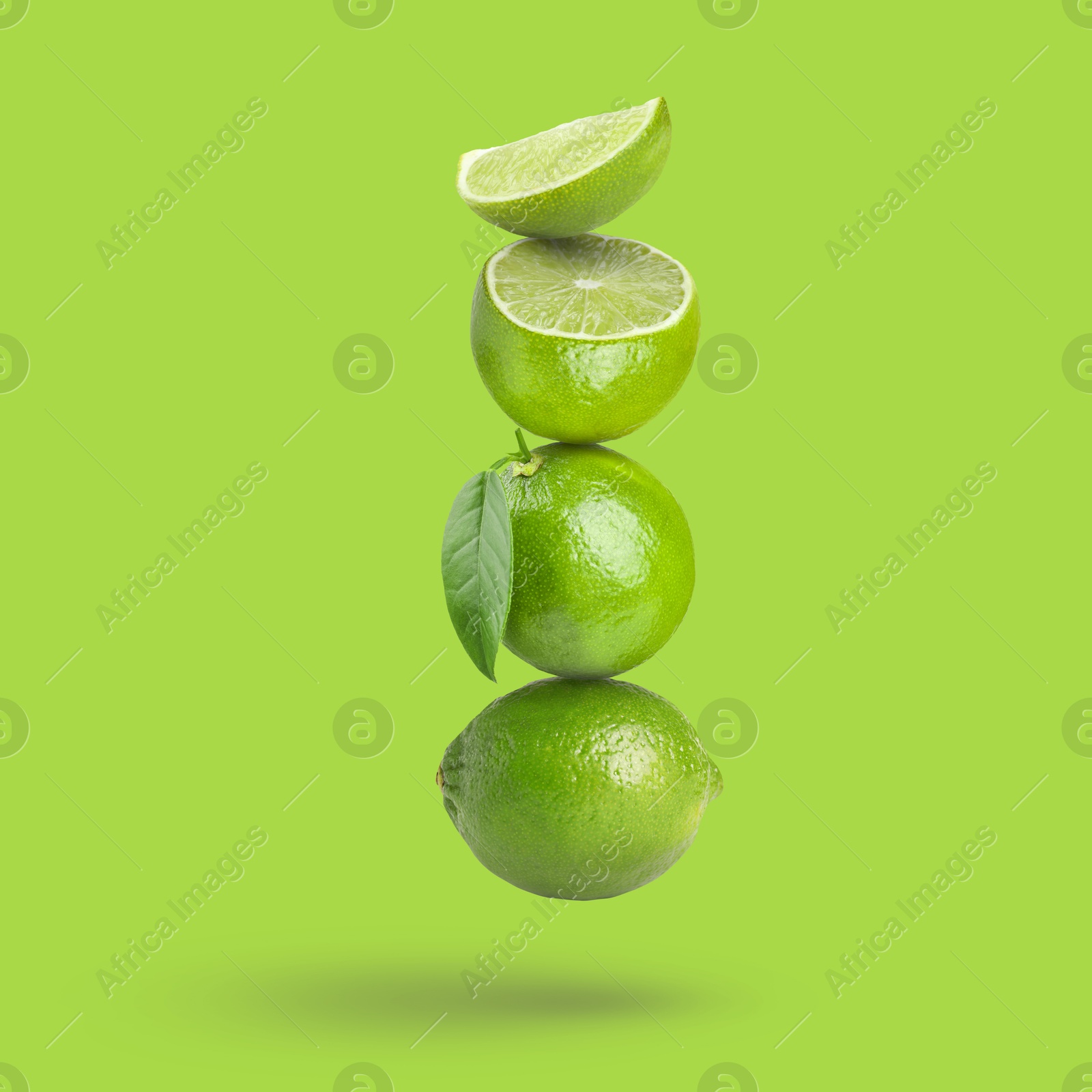 Image of Fresh juicy limes falling on light green background