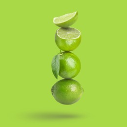 Image of Fresh juicy limes falling on light green background