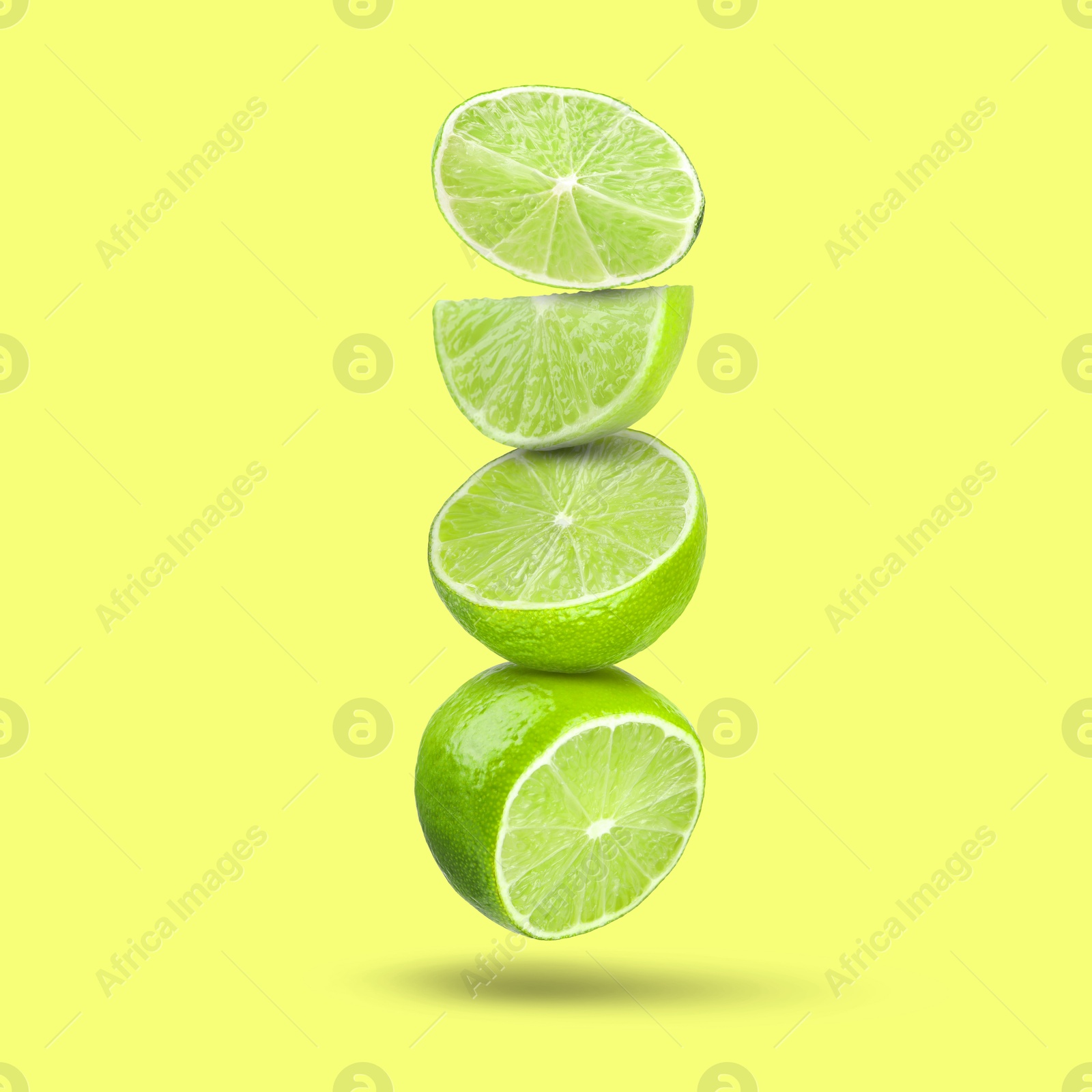 Image of Fresh juicy limes falling on yellowish green background