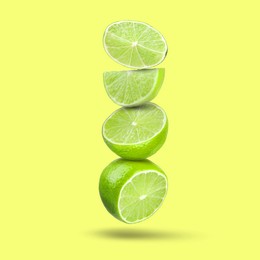 Image of Fresh juicy limes falling on yellowish green background