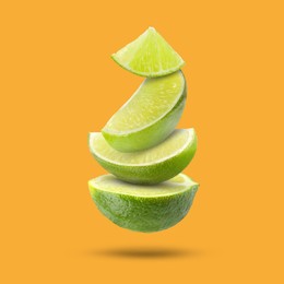 Image of Fresh lime slices falling on orange background