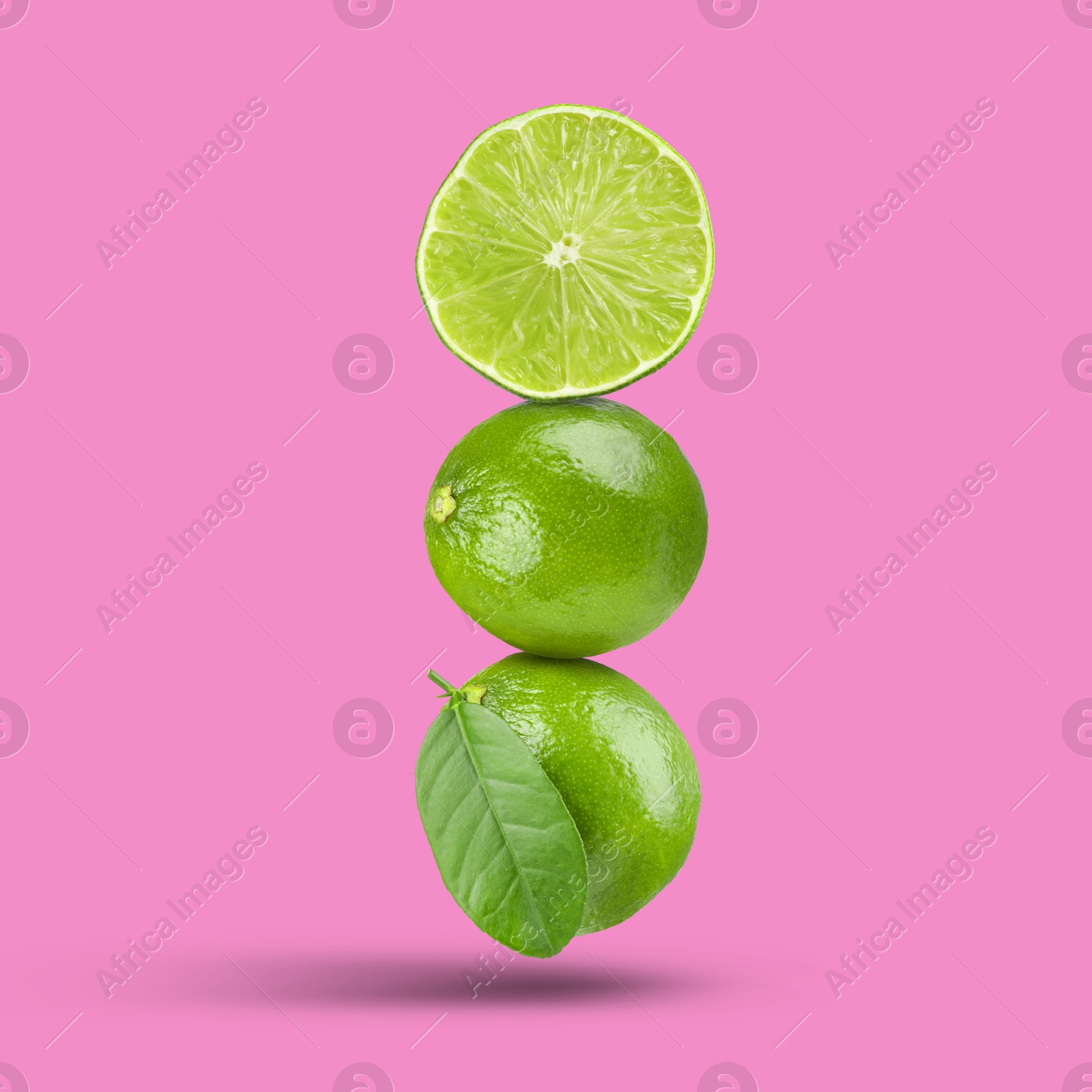 Image of Fresh juicy limes falling on fuchsia color background