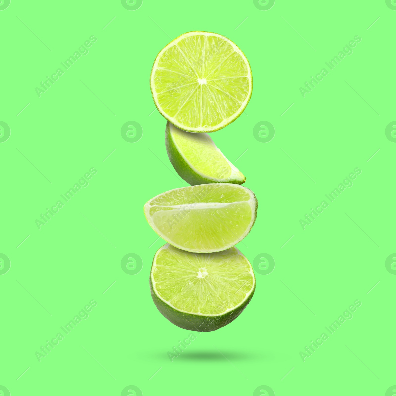 Image of Fresh lime slices falling on light green background