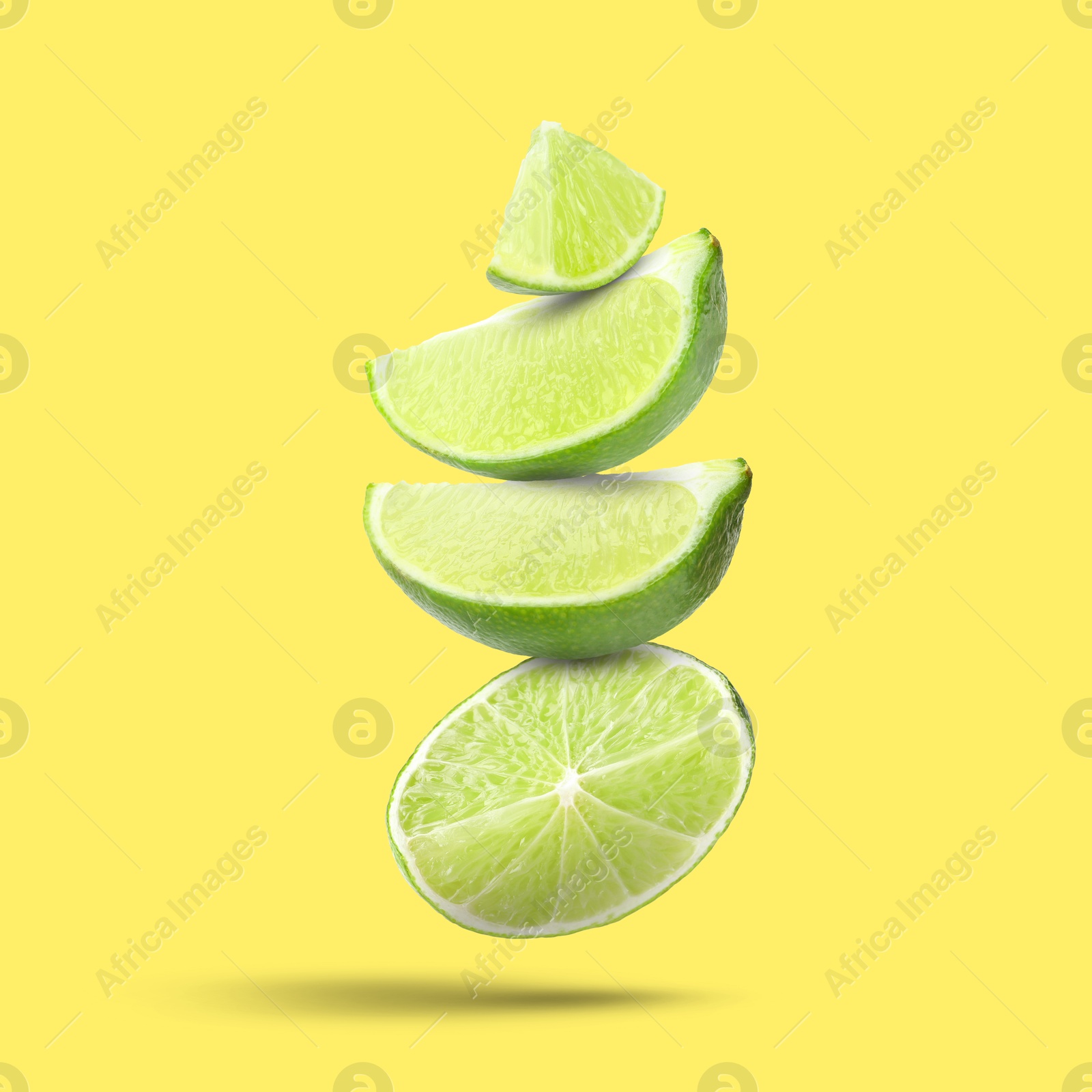 Image of Fresh lime slices falling on yellow background