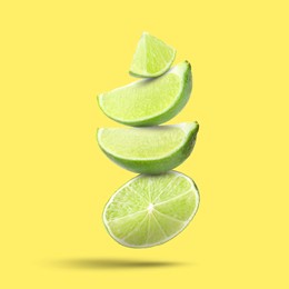 Image of Fresh lime slices falling on yellow background