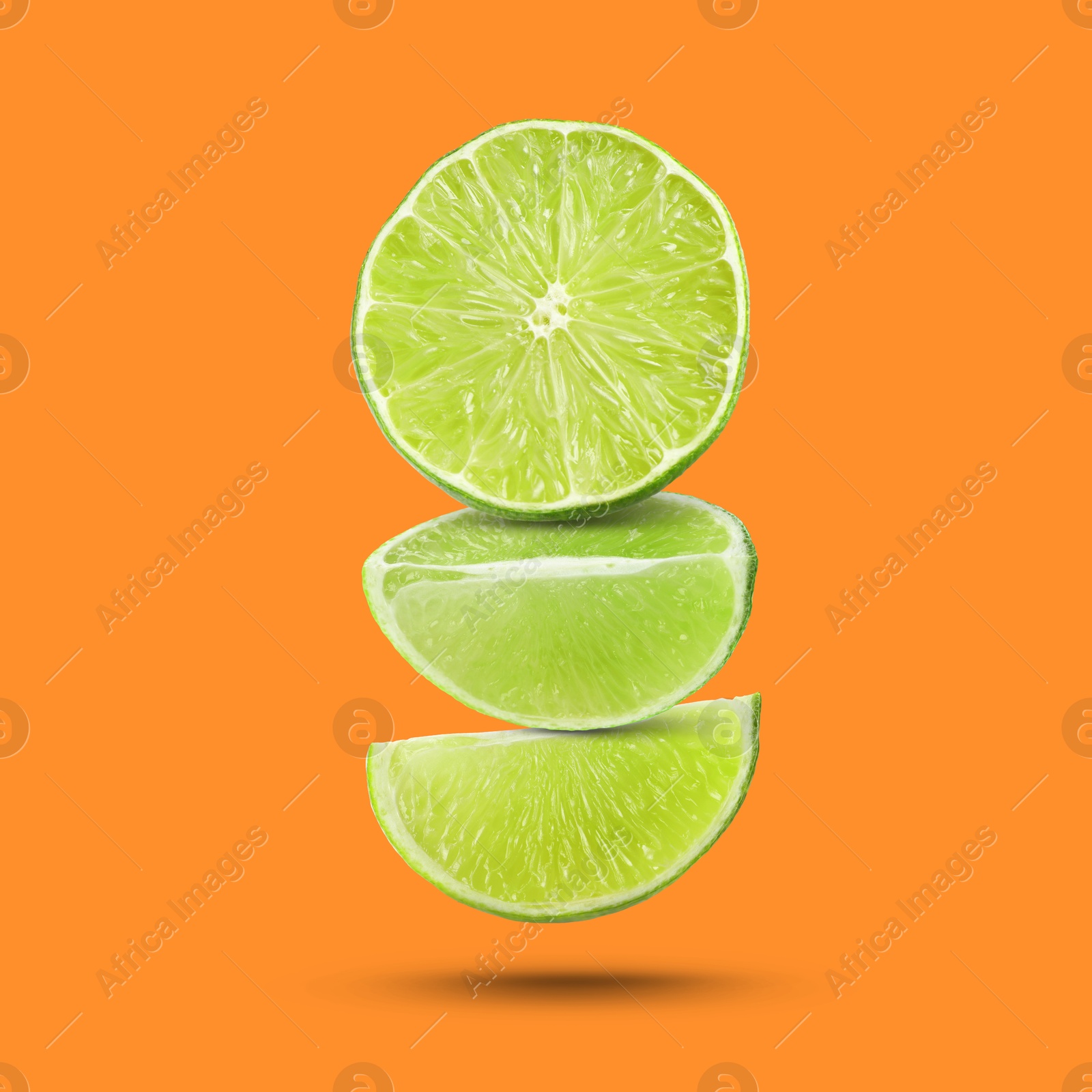 Image of Fresh lime slices falling on dark orange background