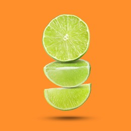 Image of Fresh lime slices falling on dark orange background