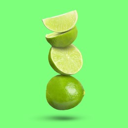 Image of Fresh juicy limes falling on light green background