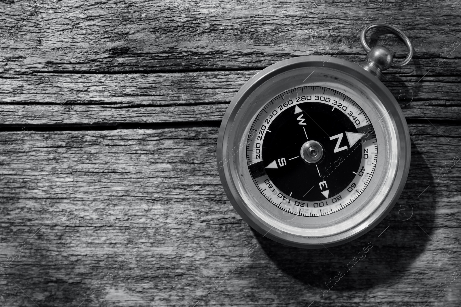 Image of Compass on wooden background, toned in black-and-white. Space for text