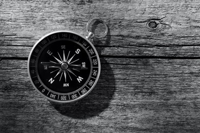 Image of Compass on wooden background, toned in black-and-white. Space for text