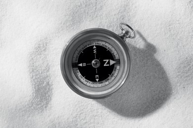 Image of Compass on sand, top view. Toned in black-and-white