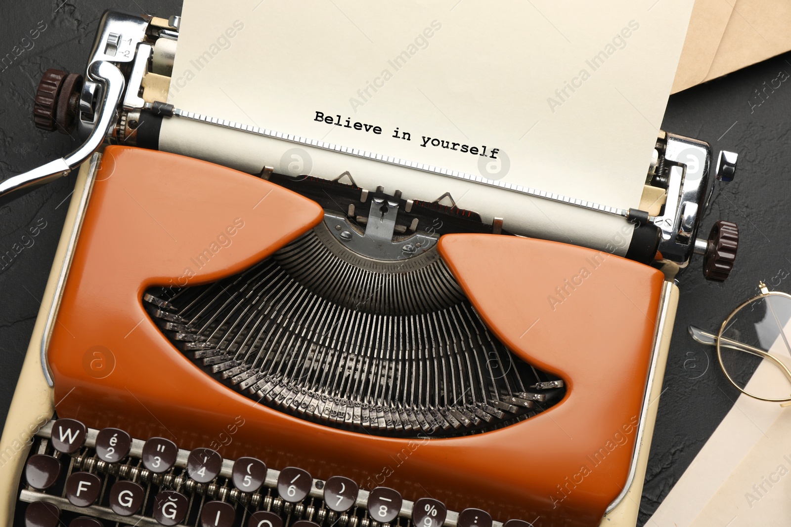 Image of Typewriter with sheet of paper on table, top view. Typed text Believe In Yourself